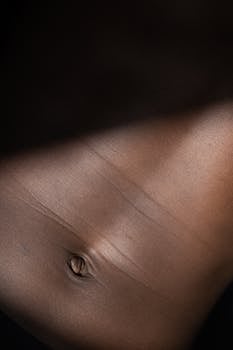 Detailed close-up of an adult's abdomen showcasing skin texture and natural light play.