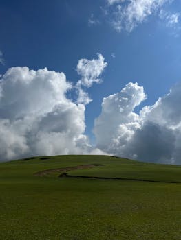Breathtaking view of clouds over a lush green grassfield in Kashmir, HP, India.