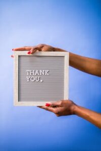 Hands holding thank you sign on blue backdrop, perfect for social media and digital marketing.