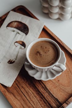 A cup of coffee elegantly presented on a wooden tray beside a mushroom-illustrated napkin.