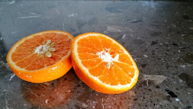 Close-up of fresh juicy orange halves showing seeds and vibrant color on a marble surface.