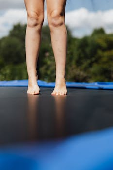 Close-up of bare feet on a trampoline outdoors with a natural blurred background.