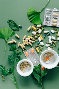 Flat lay of assorted pills and herbs on green surface, symbolizing health and wellness.