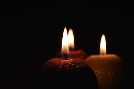 Elegant close-up of three glowing natural candles casting a warm light in the dark.
