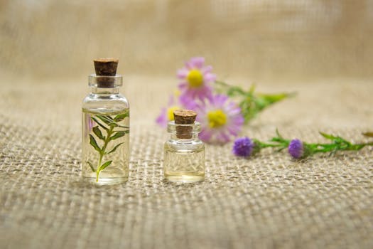 Glass bottles with essential oils and fresh flowers on burlap fabric creating a natural aromatherapy.