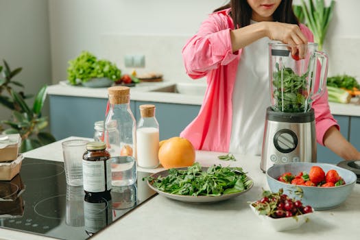 Woman in pink using high-power blender with fresh fruits and veggies for a healthy smoothie.