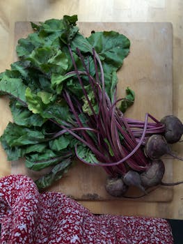 Top view of fresh beets with lush green leaves on a wooden cutting board. Perfect for healthy recipes.