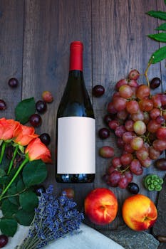 A vibrant display of wine, fresh grapes, peaches, and roses on a wooden surface.