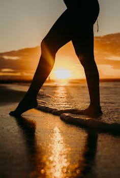 A captivating silhouette of a woman standing at the beach during a stunning sunset.