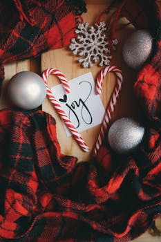 A cozy Christmas flat lay featuring candy canes, ornaments, and plaid scarf creating a joyful holiday mood.