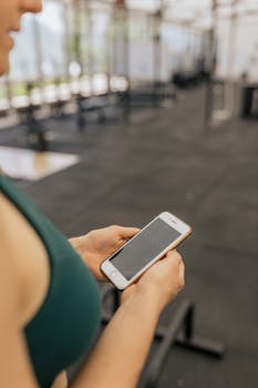 Woman checks tracking information on smartphone while working out in gym.