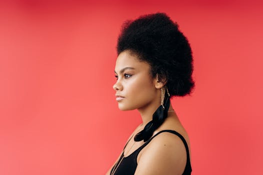 Profile view of a woman with afro hairstyle against a red background. Studio shot.