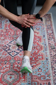 Close-up of a woman's leg stretching on an ornate carpet for fitness routine.