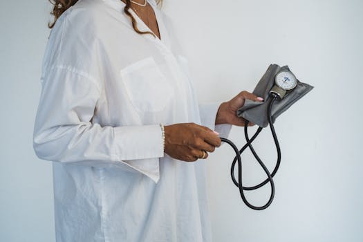 A healthcare professional in white holding a sphygmomanometer, demonstrating medical care.