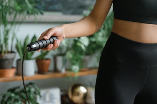 A woman in sportswear holds a jump rope, ready for a workout session indoors.