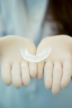 Focused image of gloved hands presenting a transparent dental retainer, emphasizing dental hygiene.