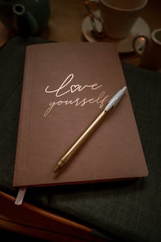 Inspirational notepad with 'love yourself' message in a cozy cafe setting, Manchester.