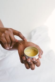 Close-up of a hand applying natural skincare cream, emphasizing self-care and holistic health.