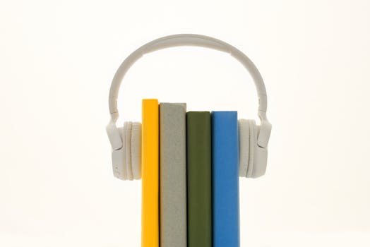 White headphones resting on colorful books, symbolizing modern audio technology.