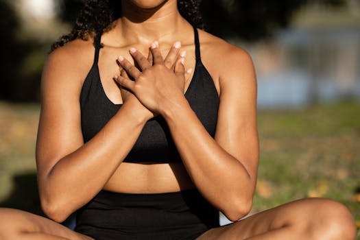 A woman in activewear practices mindfulness meditation outdoors, hands on chest.