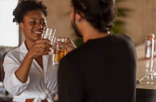Two friends clinking beer glasses in a cozy bar setting, enjoying a casual moment.
