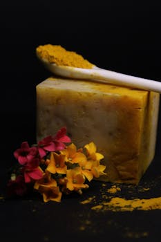 Artistic shot of handmade curcuma soap with flowers and turmeric powder.
