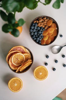 Vibrant flat lay of mixed fruits and nuts on a white background.