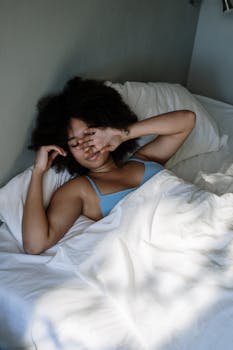 Woman awakening gently in a cozy bedroom, embracing a relaxed morning vibe.