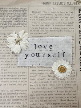Close-up of vintage paper with 'Love Yourself' text and pressed flowers, evoking nostalgia and self-care.
