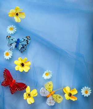 Brightly colored artificial butterflies and flowers on a blue fabric backdrop.