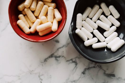 Top view of red and black ceramic bowls filled with assorted capsules on marble surface.