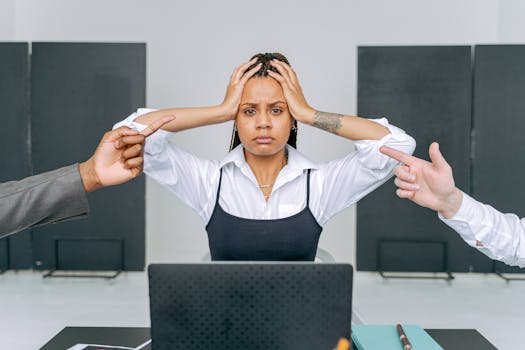 A stressed woman in an office setting receiving blame from coworkers, capturing workplace conflict.