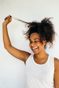 Smiling woman with curly hair enjoying a moment of joy against a white backdrop.
