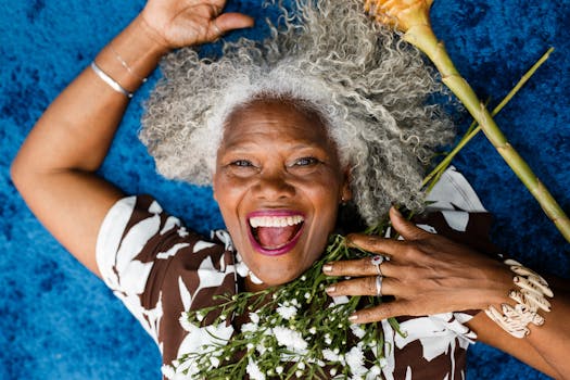 Smiling senior woman with flowers, representing happiness and vibrance against a blue background.