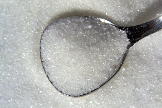 Detailed macro shot of white sugar crystals on a reflective spoon.
