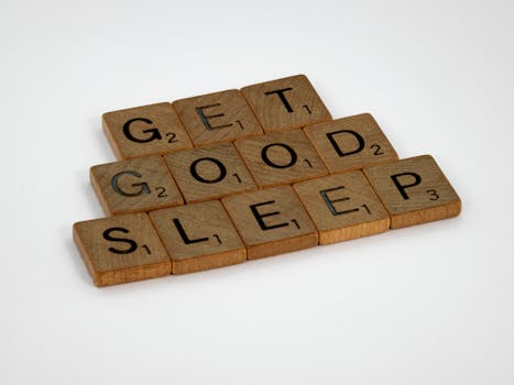Wooden Scrabble tiles arranged to spell "Get Good Sleep" on a white background.