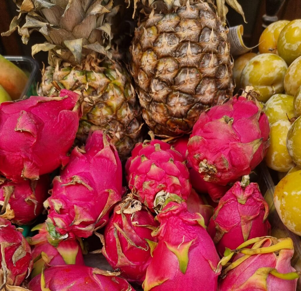 Close-up of fresh pineapples and vibrant dragon fruits in a market setting.