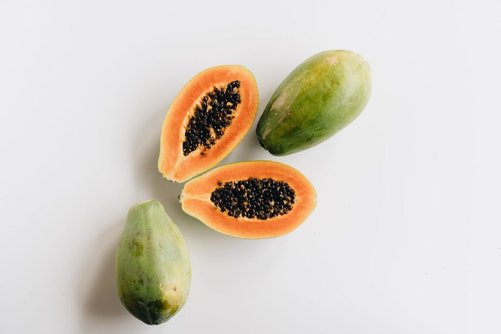 Top view of ripe papaya fruit and slices on a white surface, showcasing vibrant colors and freshness.
