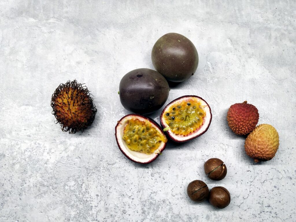 Collection of exotic fruits including passion fruit, rambutan, lychee, and macadamia nuts.