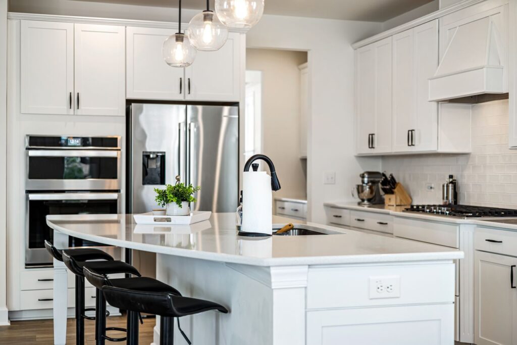 A sleek modern kitchen with white cabinets, elegant lighting, and stainless steel appliances, providing a clean and contemporary look.
