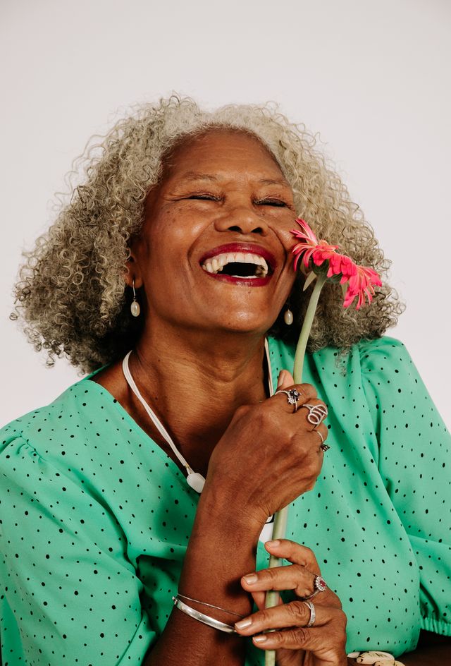 A cheerful senior woman holding a vibrant flower, exuding happiness.