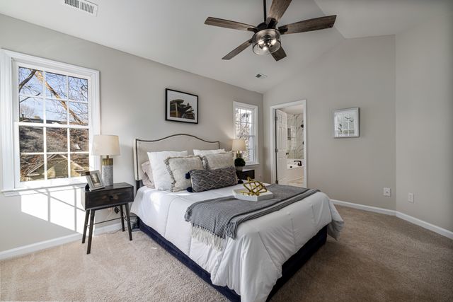 A bright, cozy bedroom featuring a ceiling fan, modern decor, and comfortable bedding.