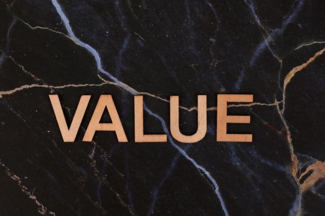A close-up of wooden 'Value' letters placed on a dark marble background, emphasizing texture and concept.
