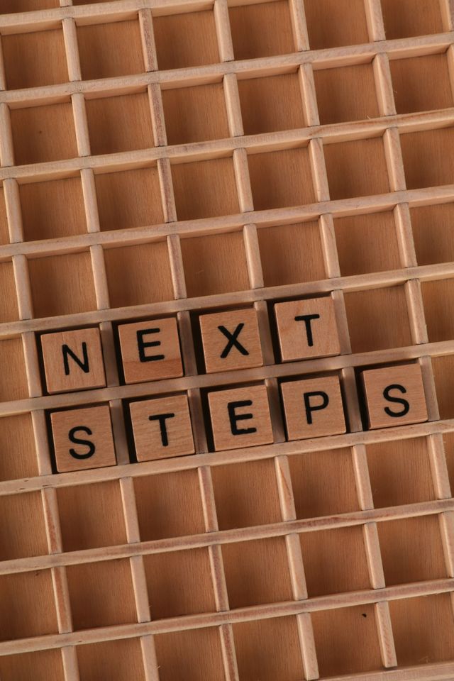 Wooden cubes arranged on a grid showing the words 'Next Steps' for motivational concept.